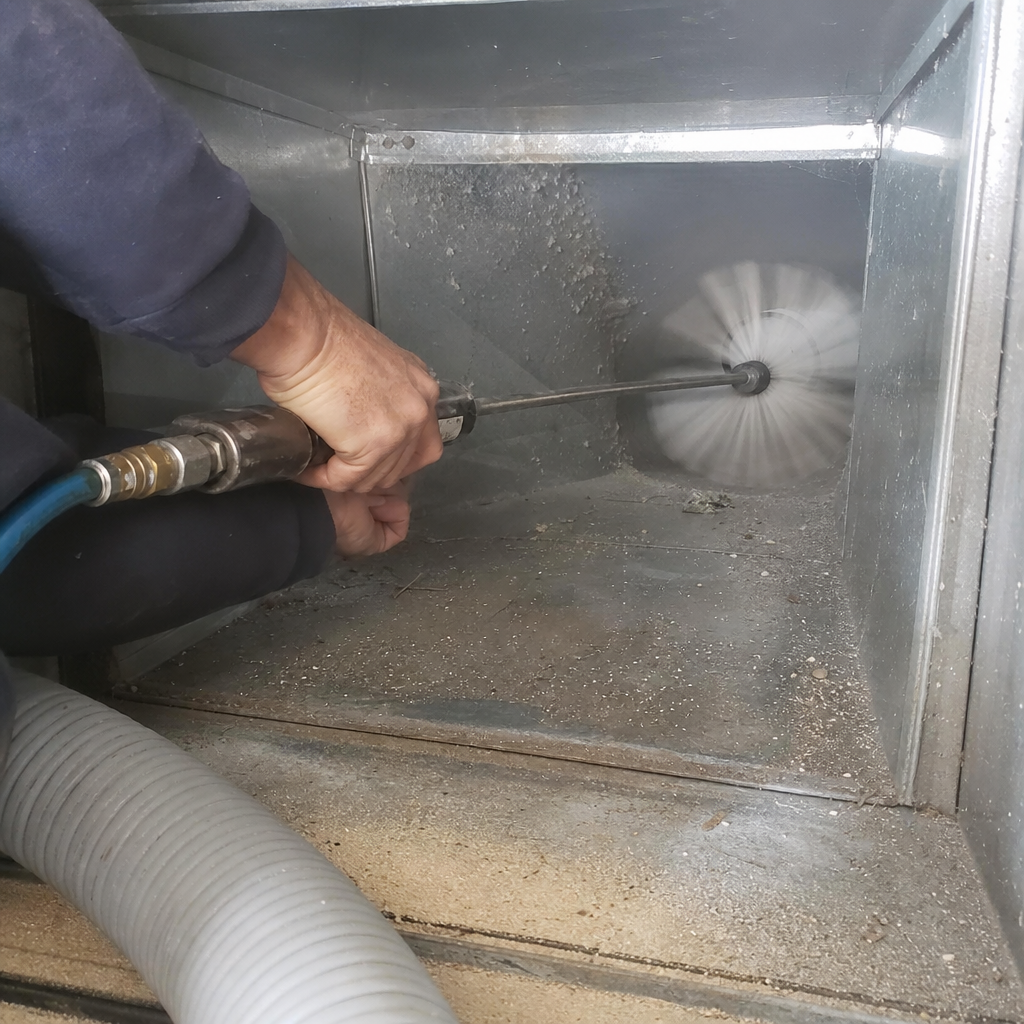 Technician using a rotating brush to clean residential metal air ducts in Harrison, OH